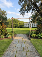 Stone ceremony path through a rustic wooden wedding arch toward a Southern estate lawn in Montgomery, Alabama